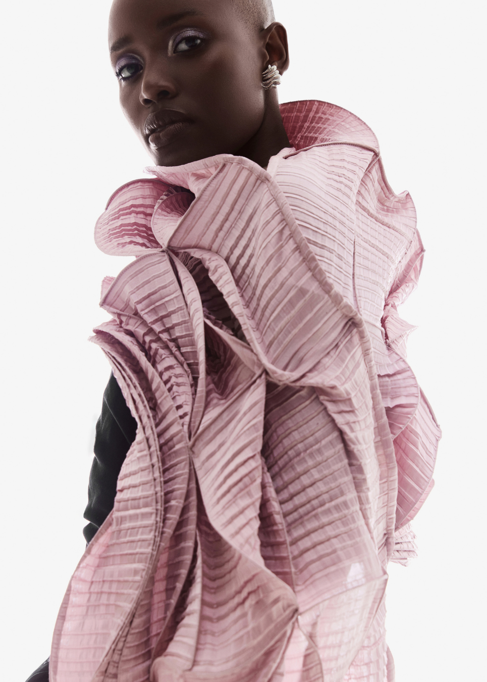 Model wearing a black dress with a pink drape against a white background