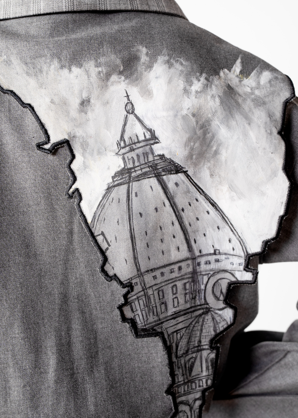 A close-up of a gray jacket with a large black-and-white graphic print of a domed building and cloudy sky, showing the shoulder and upper back area.