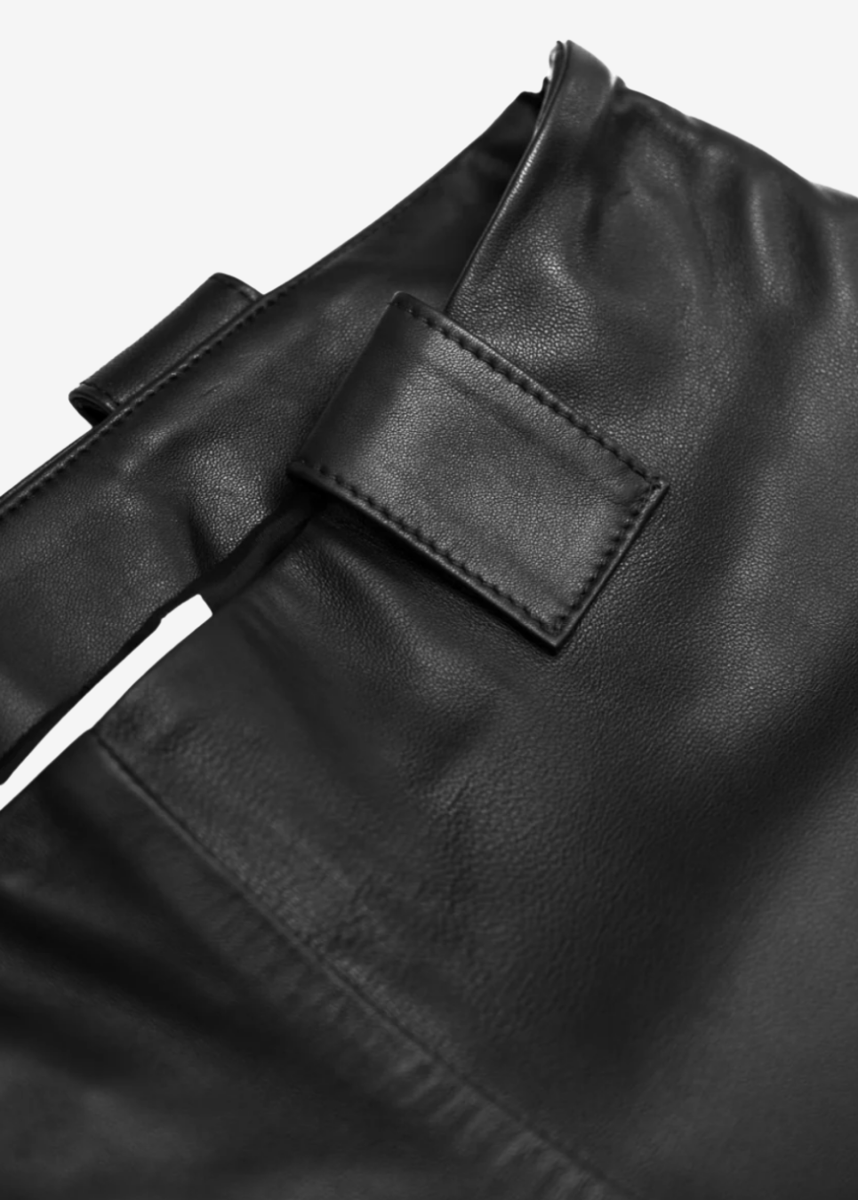 Close-up of a black leather pants with a visible brand label.