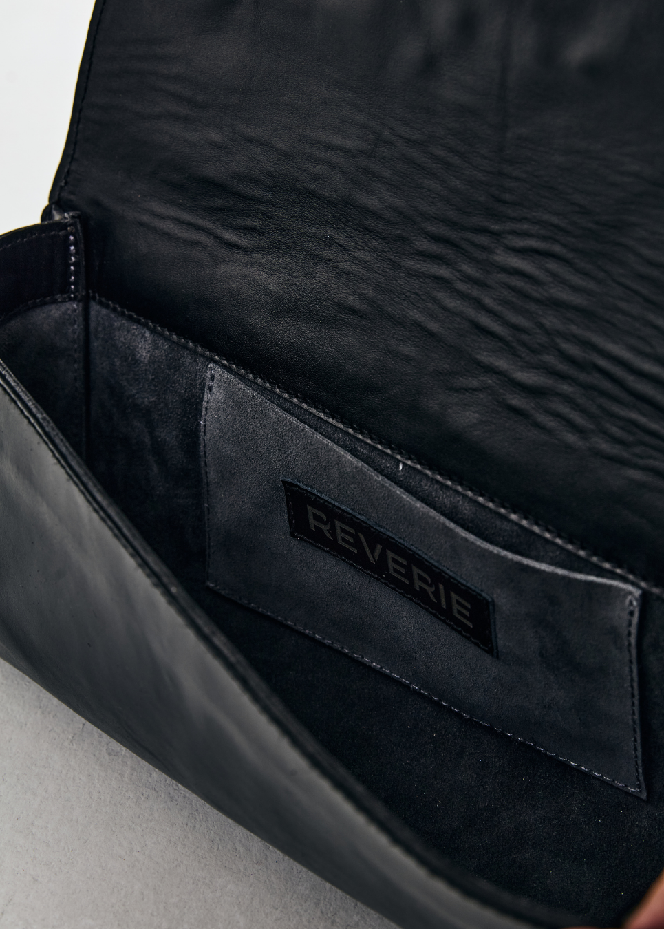 Close-up of a black leather bag with 'Reverie' branding inside.