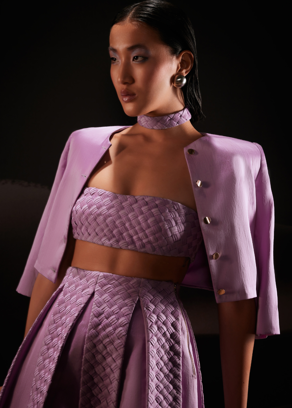 Woman wearing a purple outfit with a jacket against a dark background
