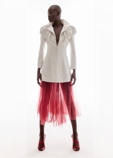 Model wearing a white jacket and red sheer skirt on a white background