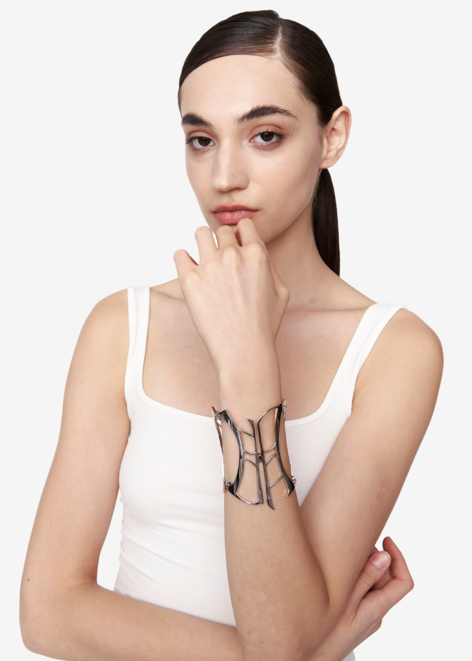A model wearing a white tank top and a black geometric wire cuff bracelet, posed against a clean white background.