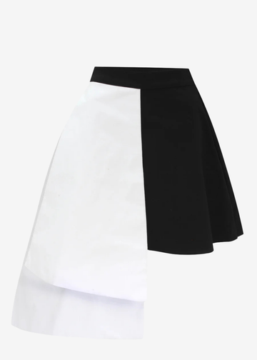 A color-blocked A-line mini skirt with a diagonal split design, featuring a solid white front panel and a solid black back panel, set against a plain light gray background.