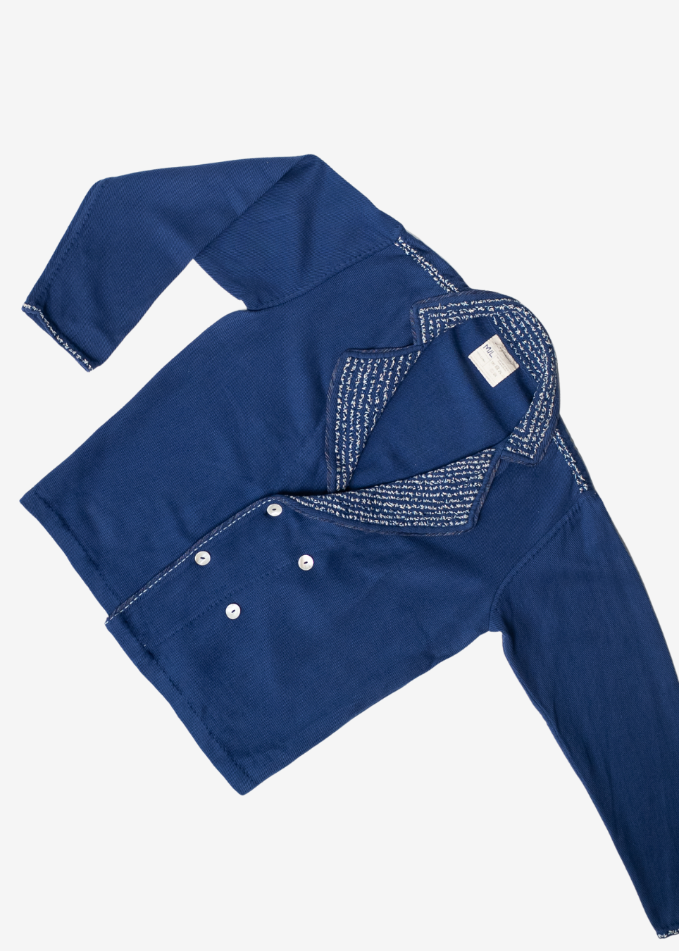 A long-sleeve indigo blue shirt with white embroidered detailing on the collar and double-button front closure, laid flat on a light gray background.