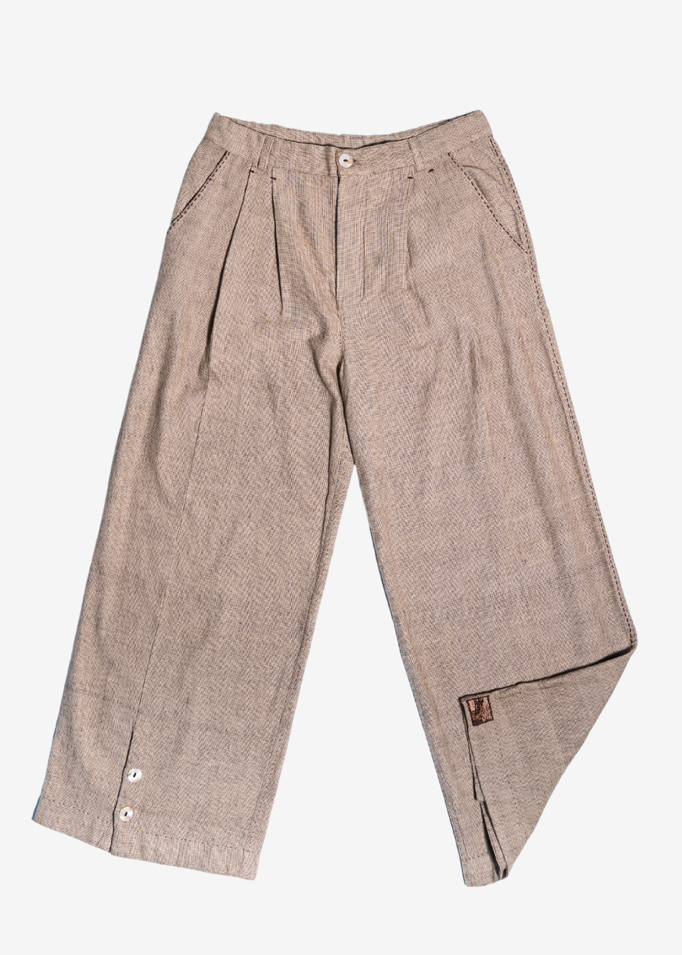 A pair of wide-leg trousers in a textured, heathered taupe-beige fabric, featuring pleated front detailing, button closures, and a small brown leather brand patch near the hem.