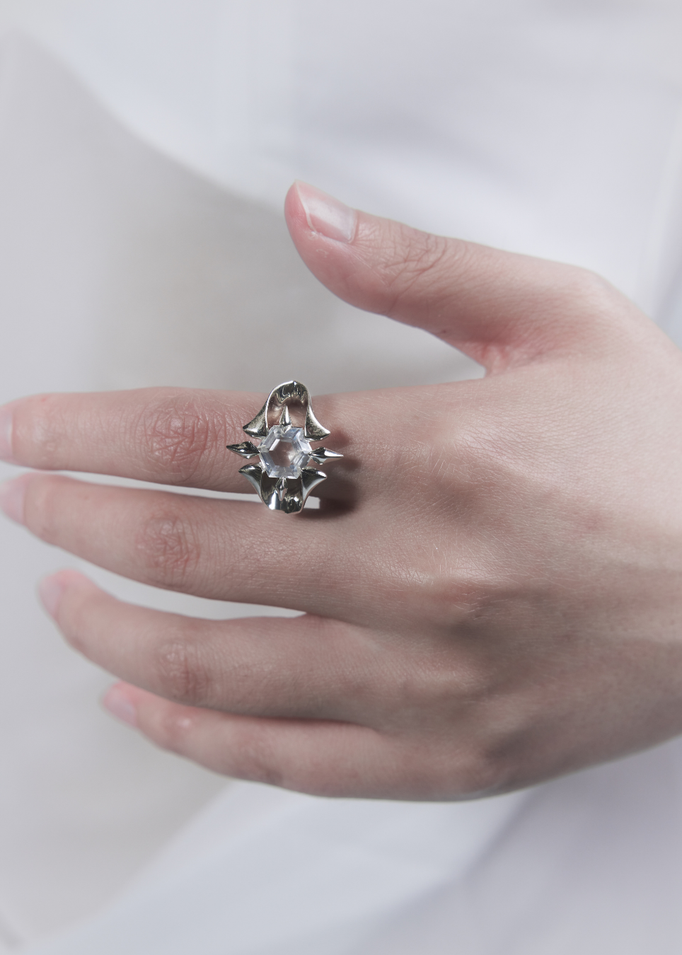 close up of a hand wearing  silver ring with a stone at the center