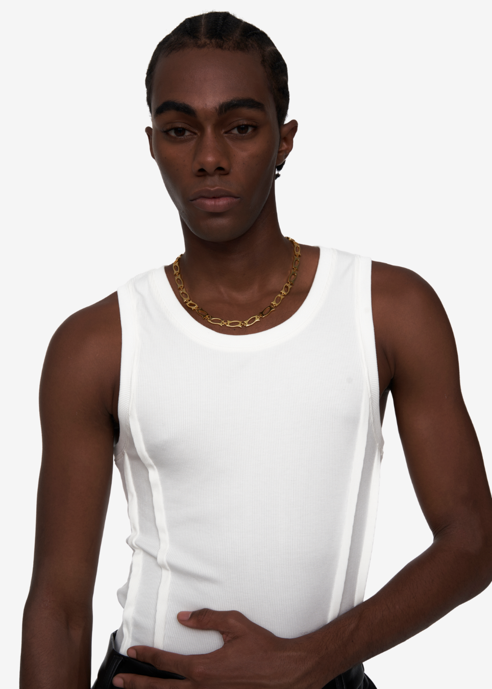 A model wearing a white ribbed tank top and a gold chain necklace, photographed against a clean white background.