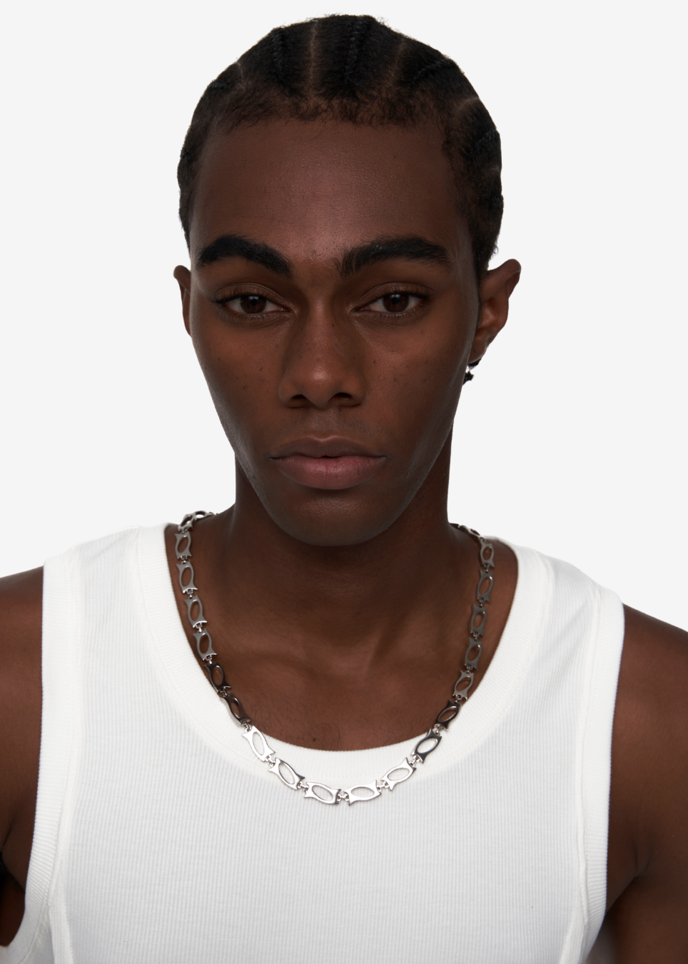 A close-up shot of a model wearing a chunky silver chain necklace with interlocking heart links, paired with a white ribbed tank top against a plain light gray background.