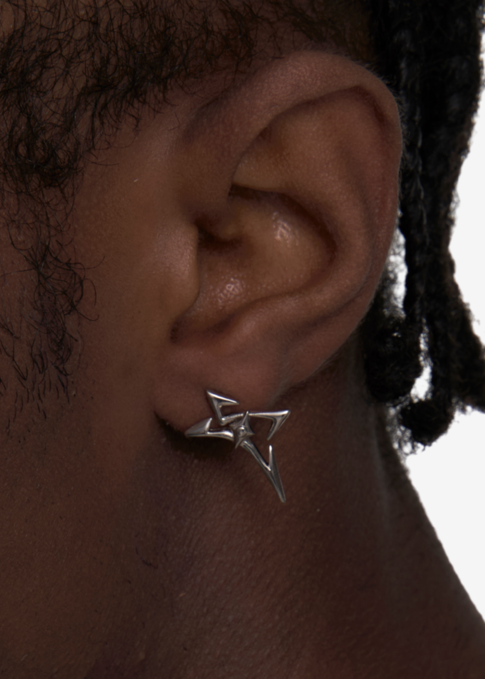 A close-up of a person's ear wearing a small silver star-shaped stud earring.