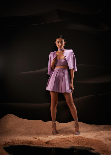 Woman in a lavender outfit standing on a dark background